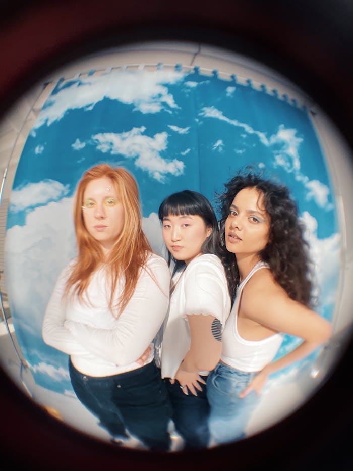 Three diverse teenage models striking a pose in a studio with fisheye lens effect.