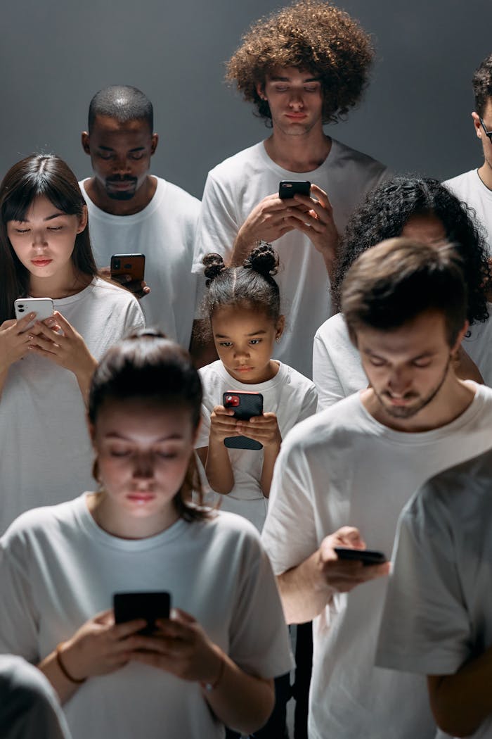A diverse group of people focused on their smartphones, symbolizing modern technologys impact on social connection.